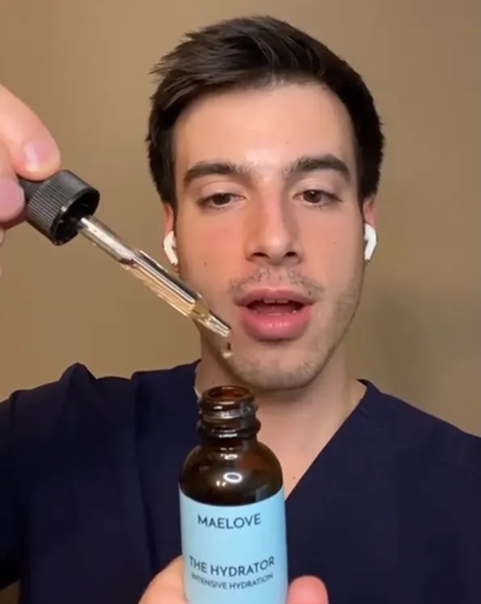 Person holding a dropper above a bottle labeled 'MAELOVE THE HYDRATOR.'