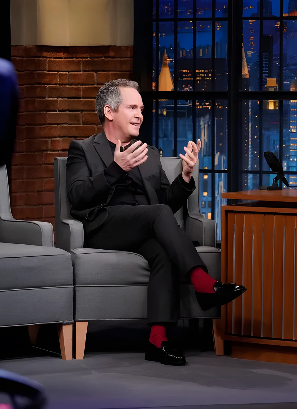 Two people talking on a late-night talk show set.