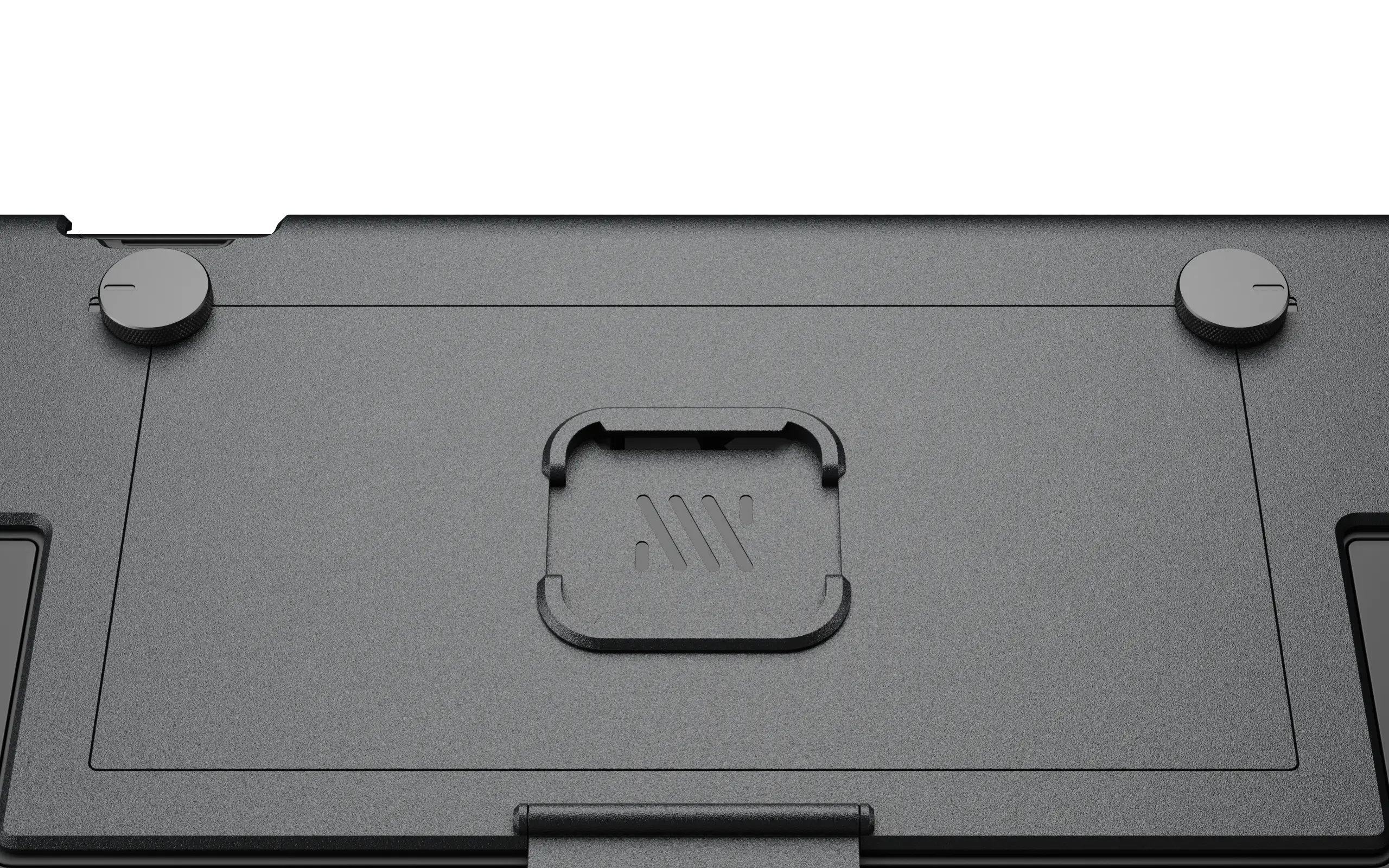 A close-up of the textured black underside of a device with round feet and a central logo.