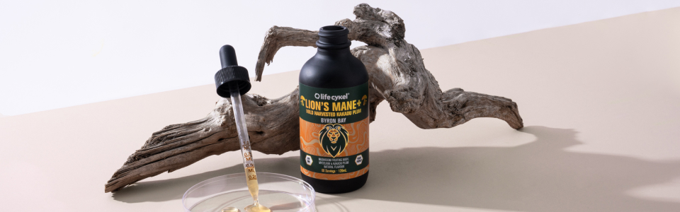 Bottle with dropper next to driftwood on a light surface.