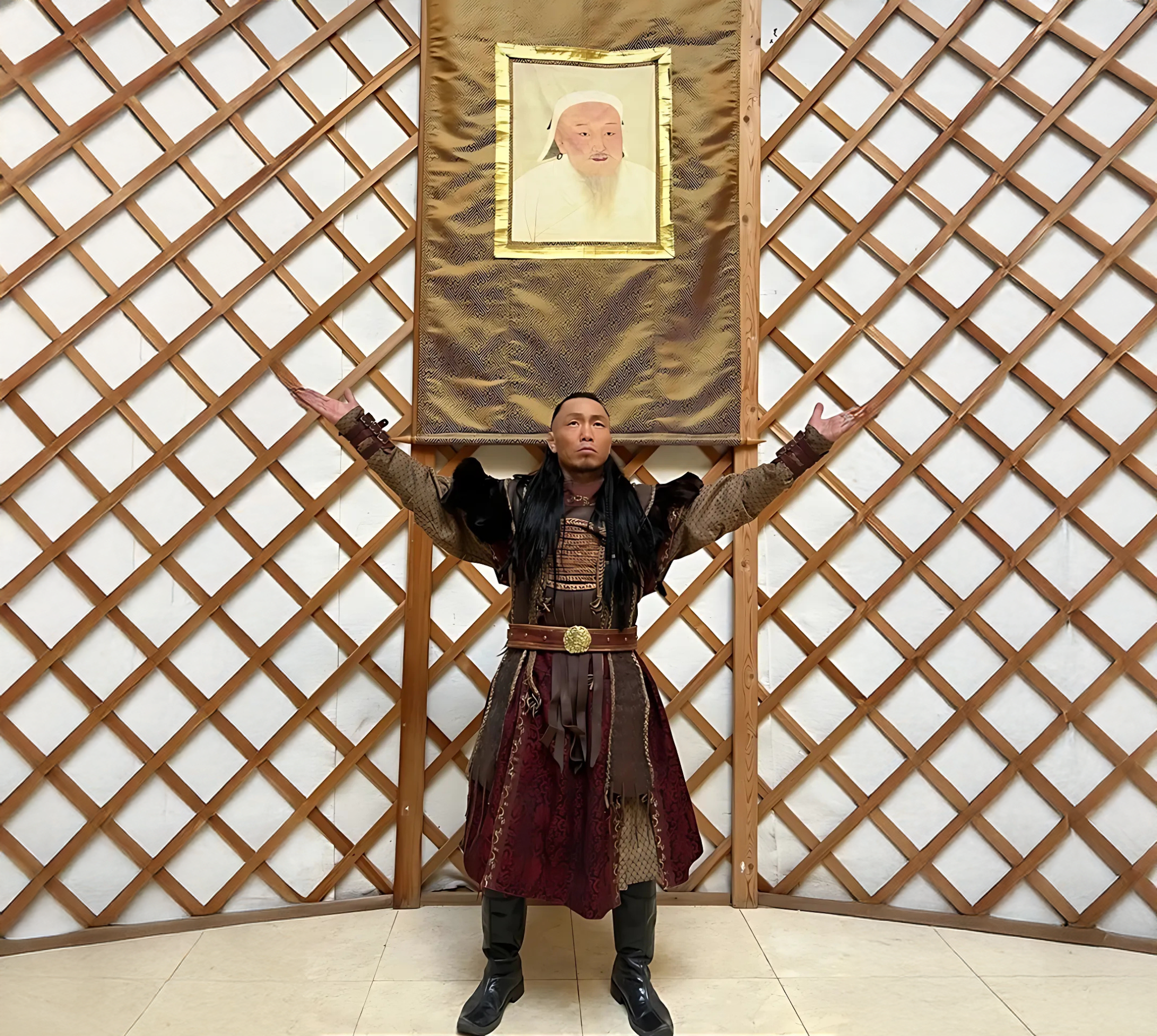 Person in traditional attire with arms raised, standing under a portrait on a lattice background.
