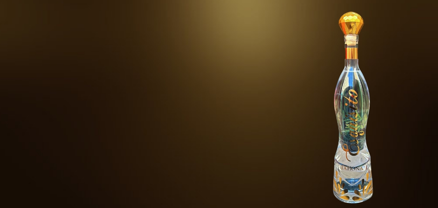 Intricately designed glass bottle with a gold stopper against a dark background.