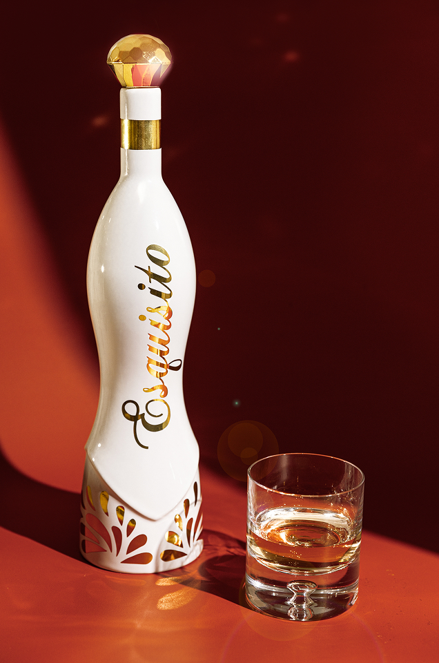 White bottle with 'Esquisito' text and a glass of liquid on a red background.