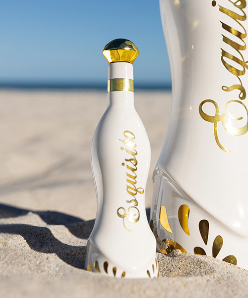 White bottle with gold accents on a sandy beach.