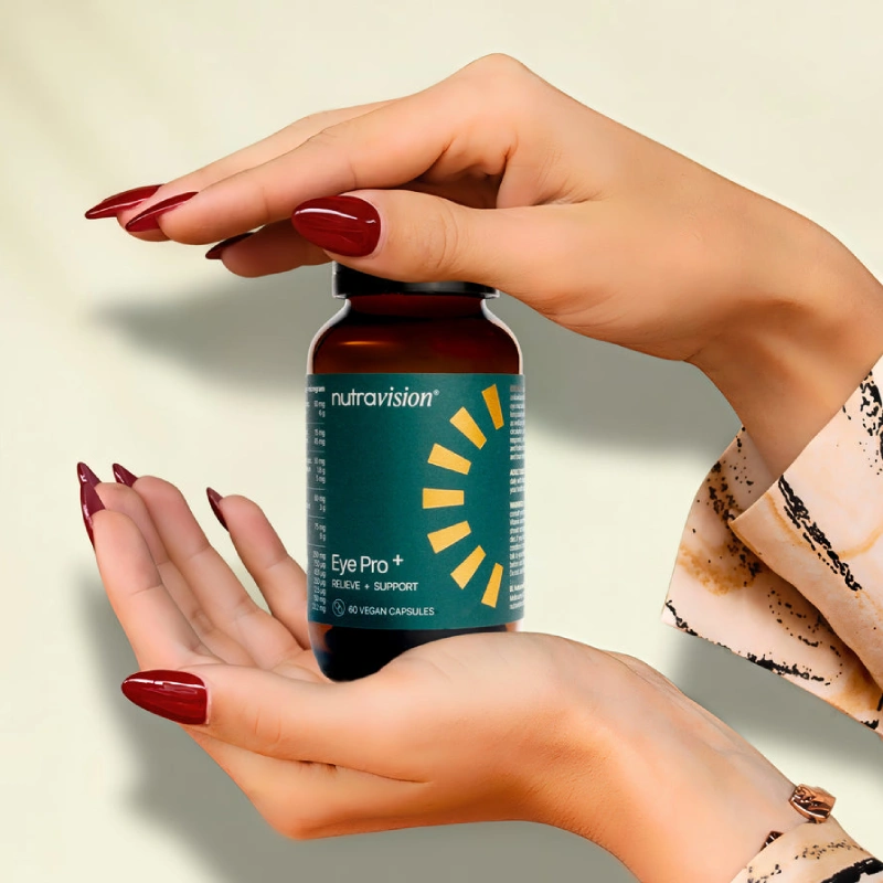 A woman's hands with red nail polish holding a bottle of Nutravision Eye Pro+ supplements.