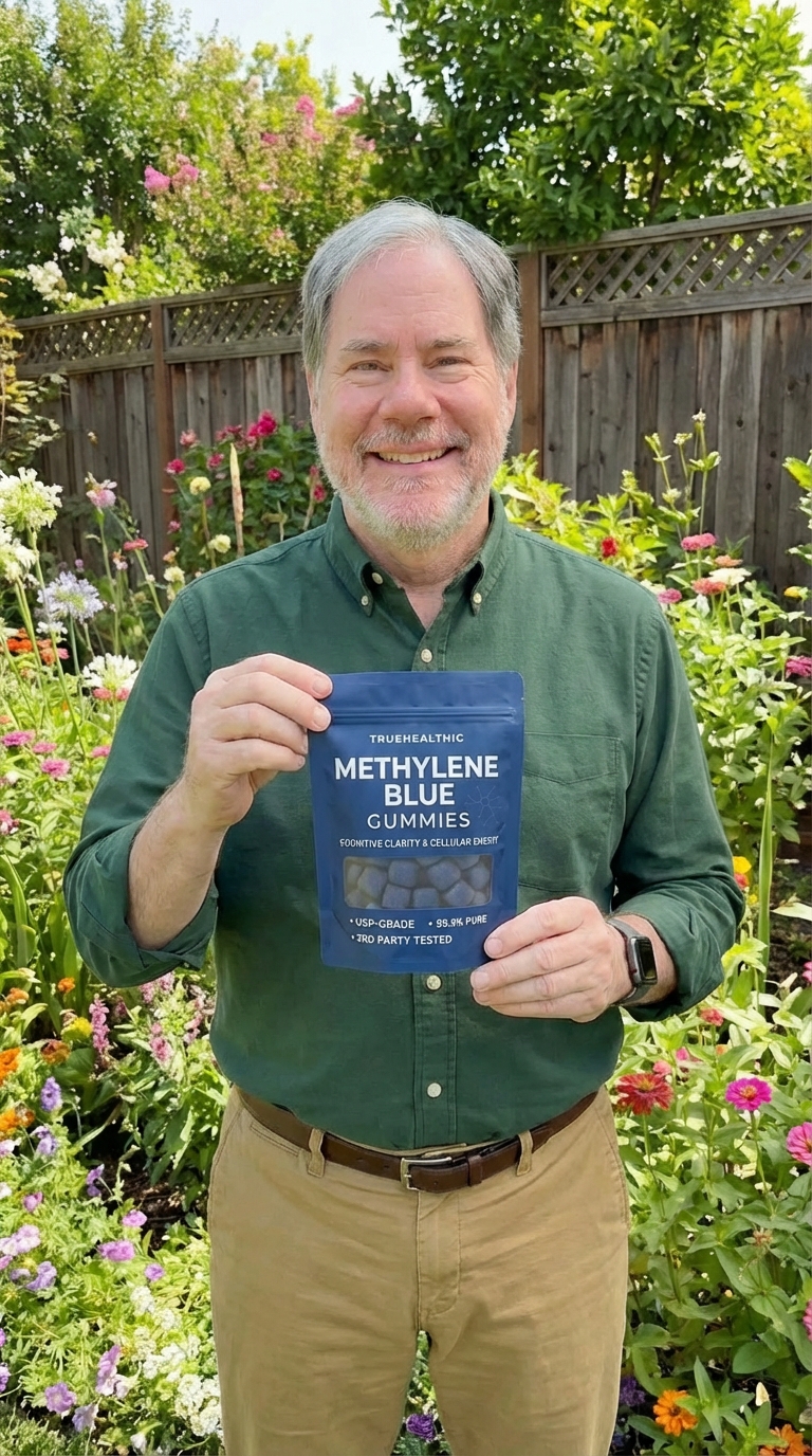 A smiling man stands in a garden holding a pouch of Methylene Blue Gummies.