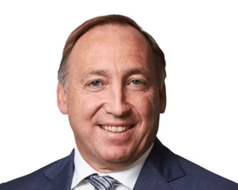 Man in a blue suit smiling against a white background.
