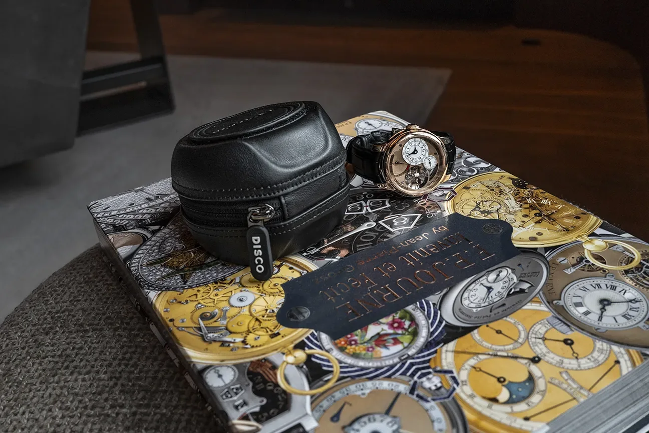 A black Tracker Puck next to an F.P. Journe tourbillon, on the F.P. Journe book