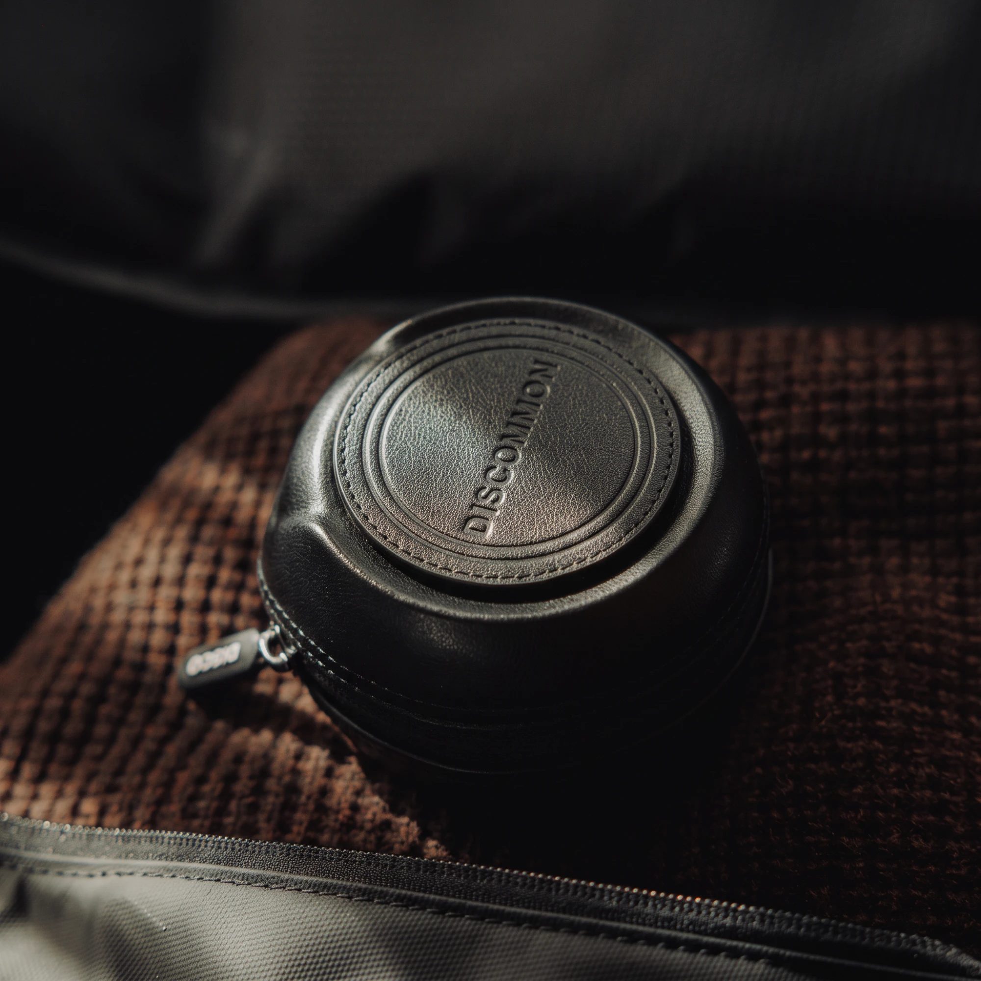 The black Tracker Puck in an open travel bag, on a brown knit