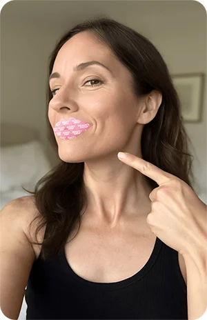 Person pointing to pink lip pattern on their face.