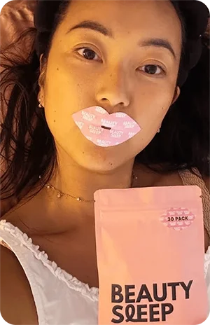 Person with lip mask holding a pink 'Beauty Sleep' package.