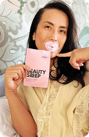 Person holding a pink beauty product package, wearing a lip mask.