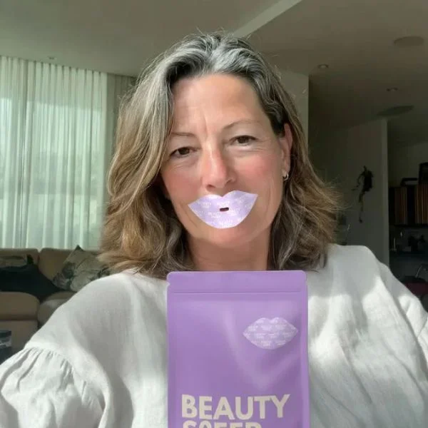 Person sleeping with pink tape over their mouth, resting on a pillow.