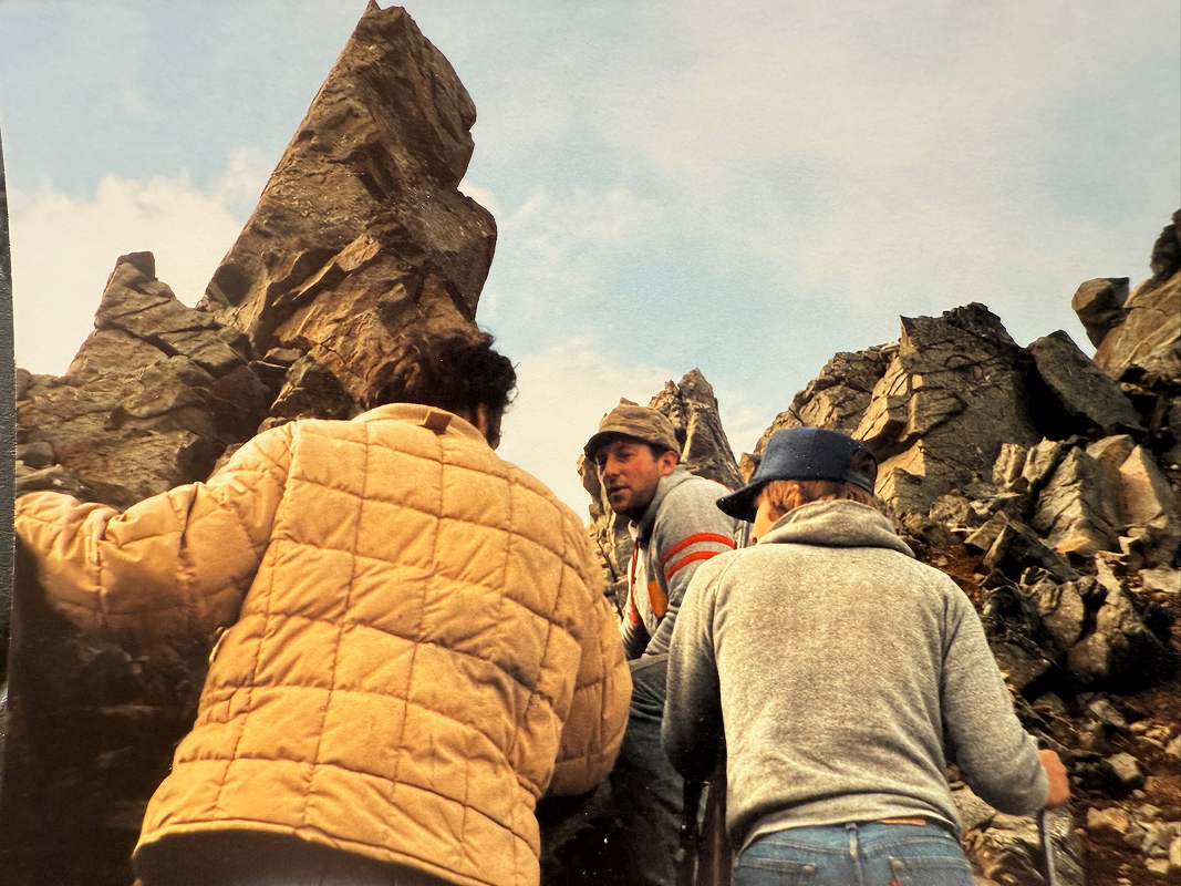 3 men with rocks in the background
