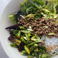 Bowl of salad with minced meat, noodles, and fresh vegetables.
