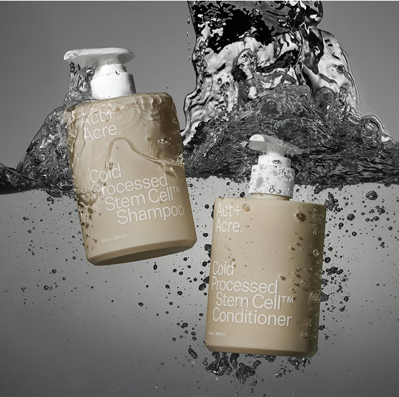 Two bottles of Act+Acre shampoo and conditioner submerged in water.