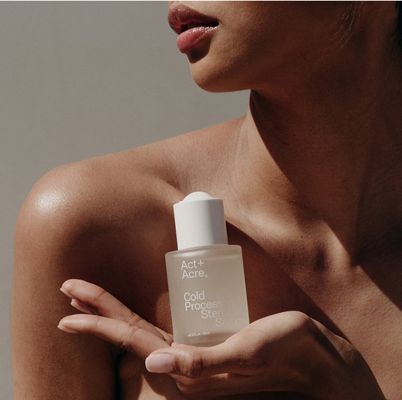 Person holding a bottle labeled 'Act + Acre Cold Processed Scalp Serum.'