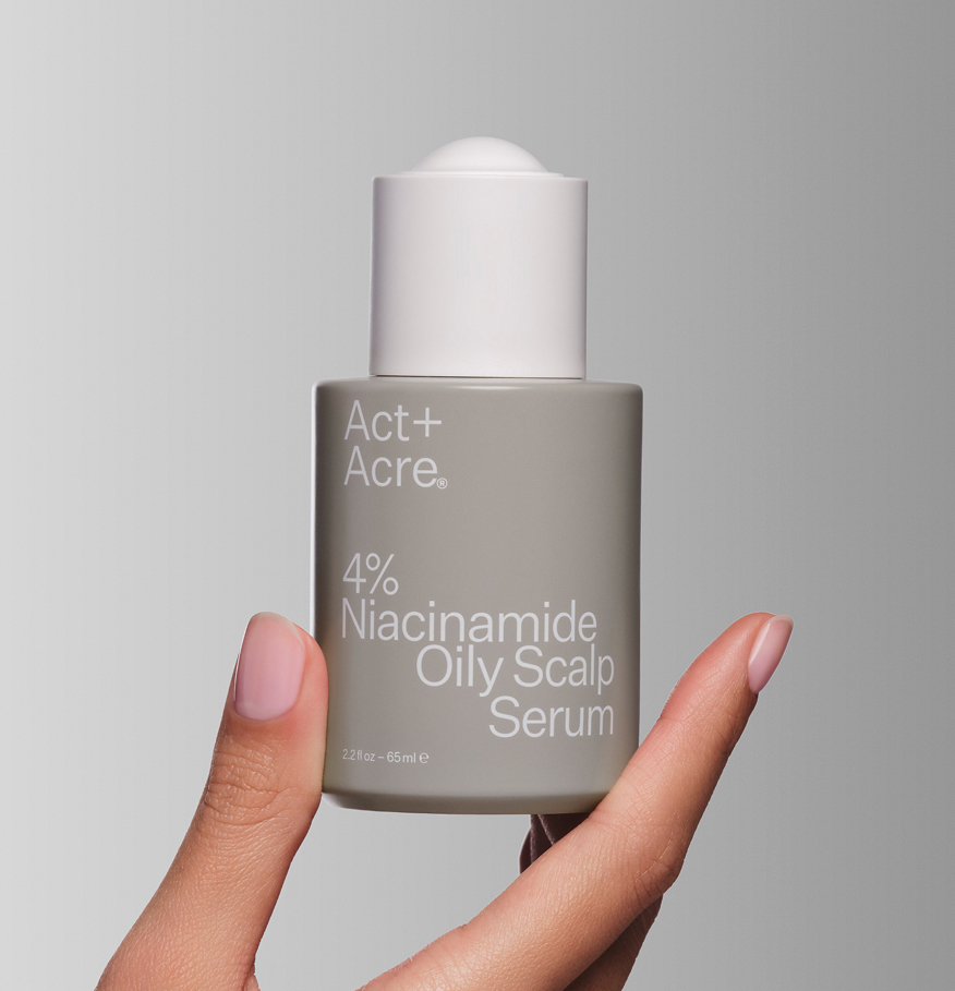 Hand holding a bottle of Act+Acre 4% Niacinamide Oily Scalp Serum.