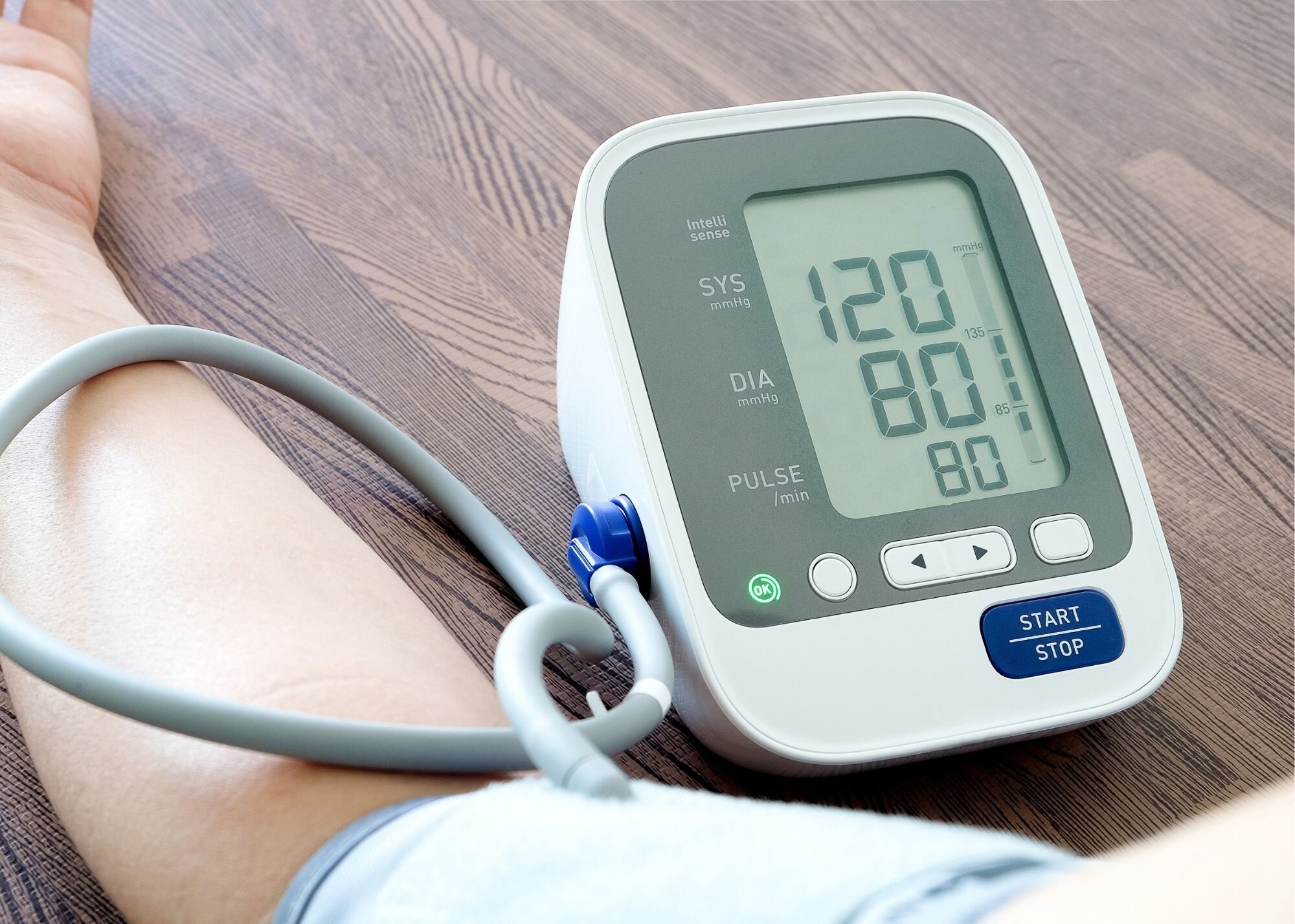 Person using digital blood pressure monitor on arm.