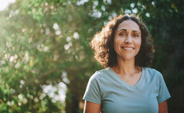A person standing outdoors, smiling, with trees in the background.