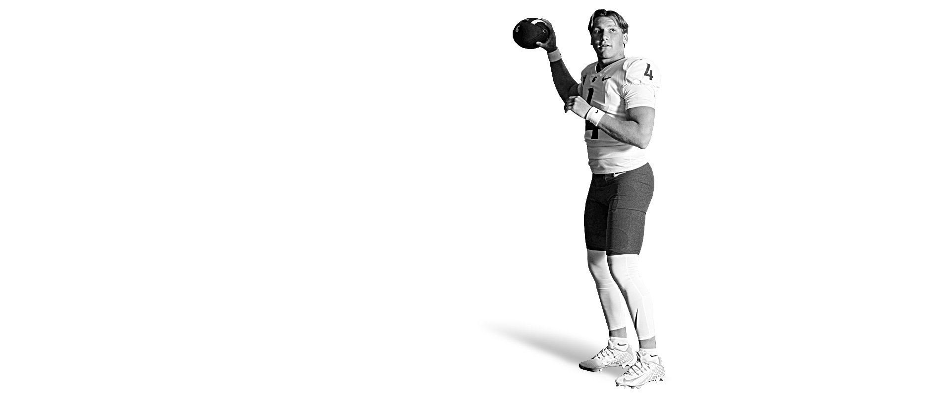 Black and white image of a football player holding a ball, wearing a uniform.