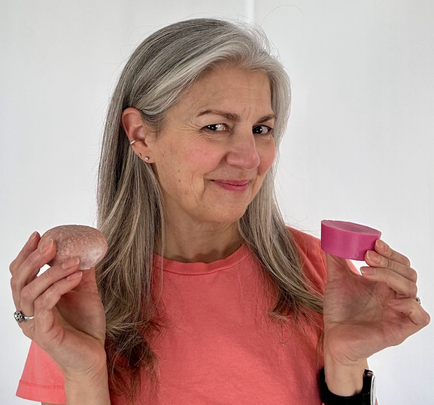 A person in a pink shirt holding two different shaped objects in their hands.