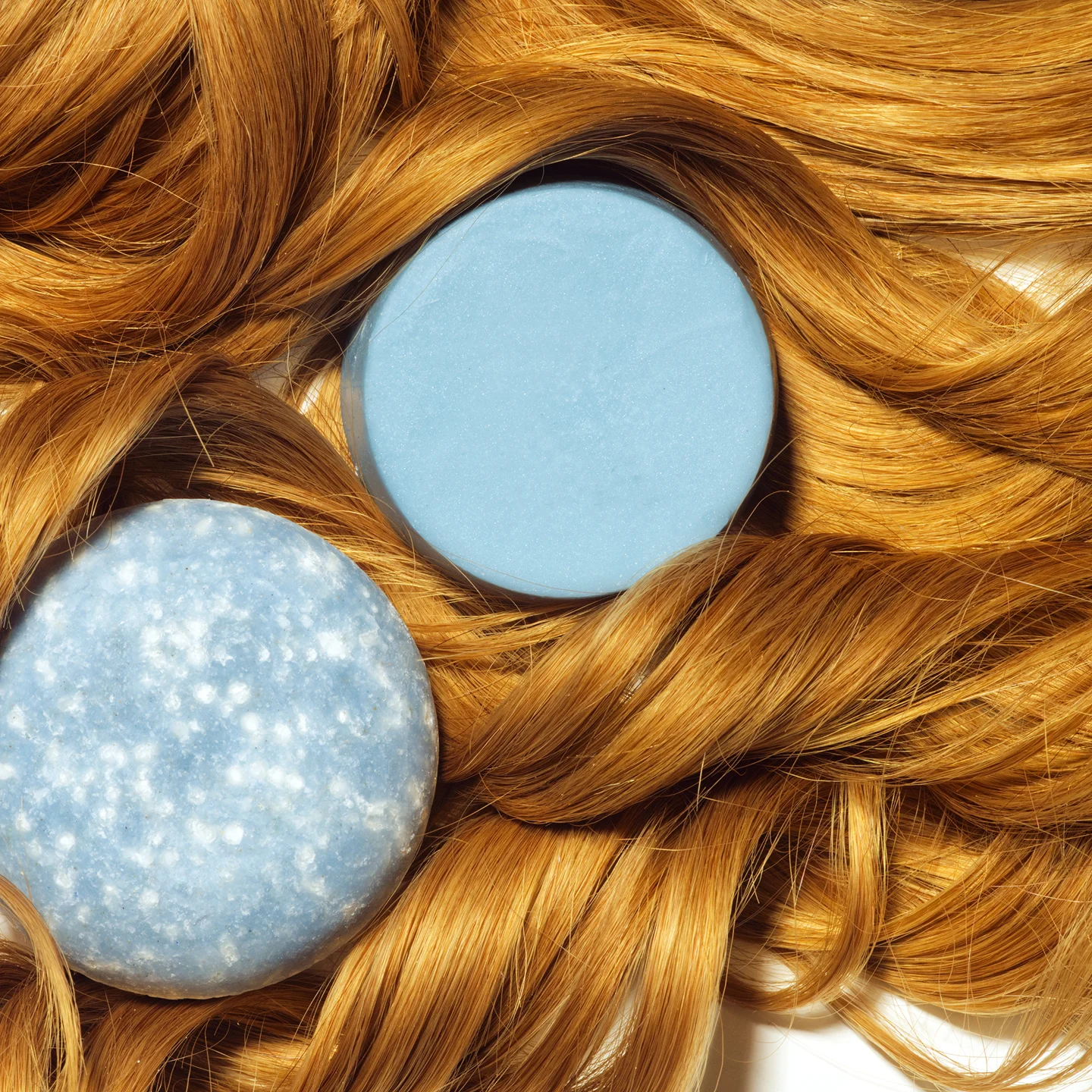 Two blue soap bars on wavy, golden brown hair.