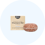 A round, reddish-brown shampoo bar rests against its beige and white packaging box.