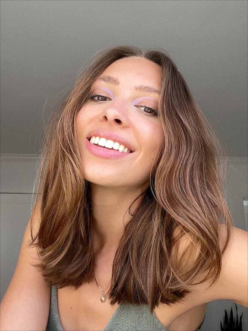 Smiling person with long brown hair and a green top.