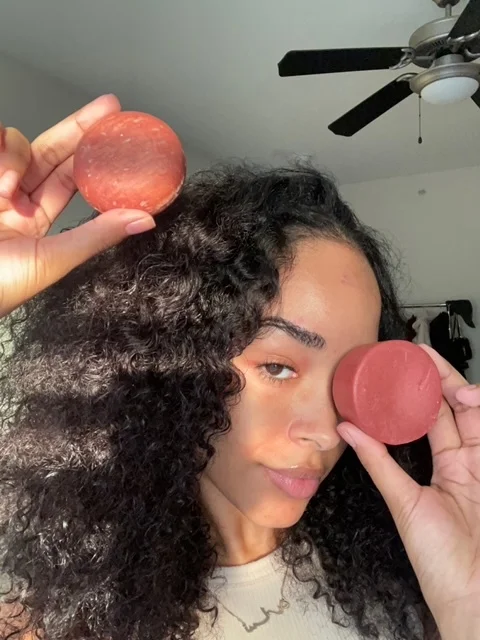 Person holding two round red objects in front of their face.