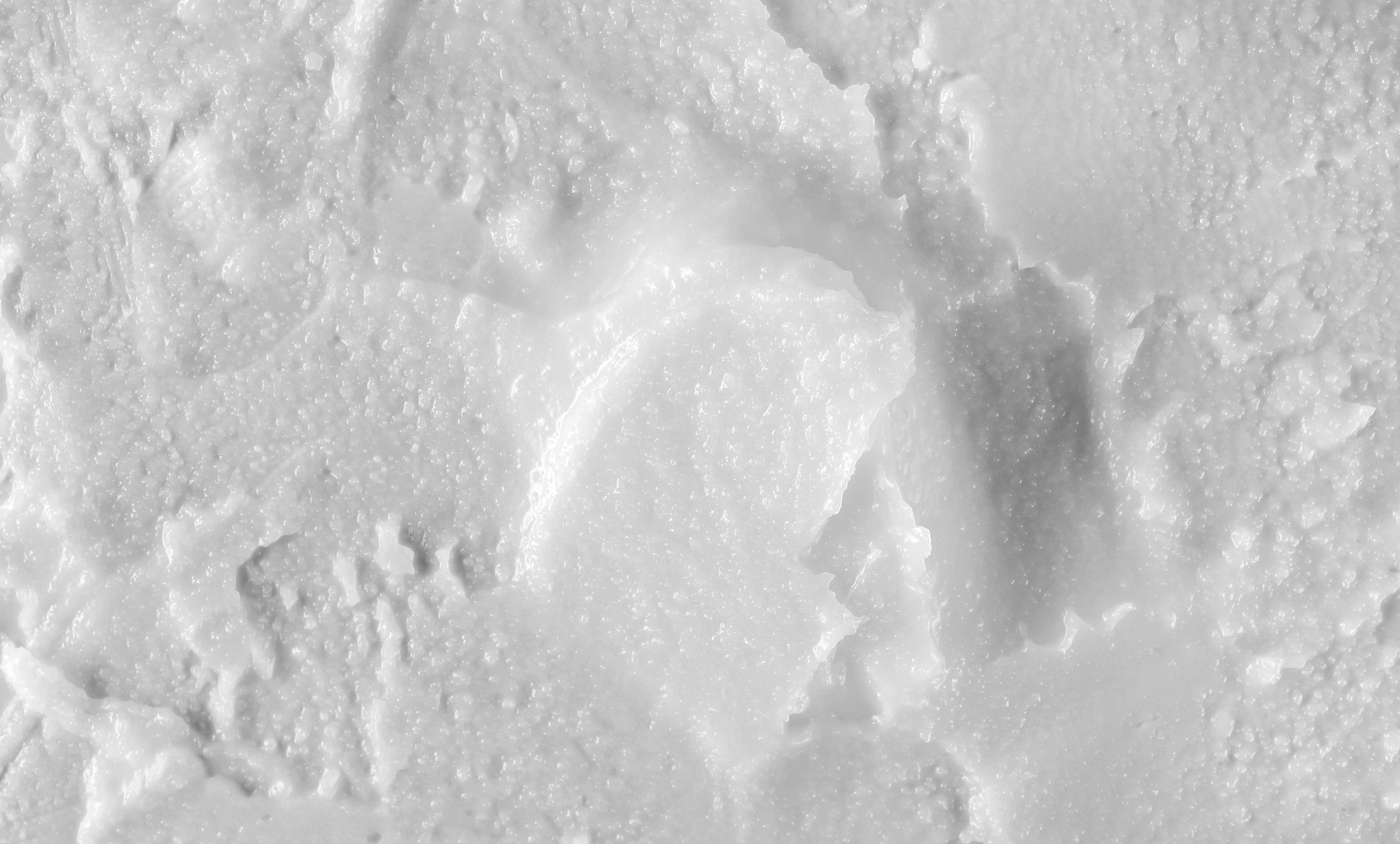 An extreme close-up, black and white photograph of the texture of a thick, white cream.