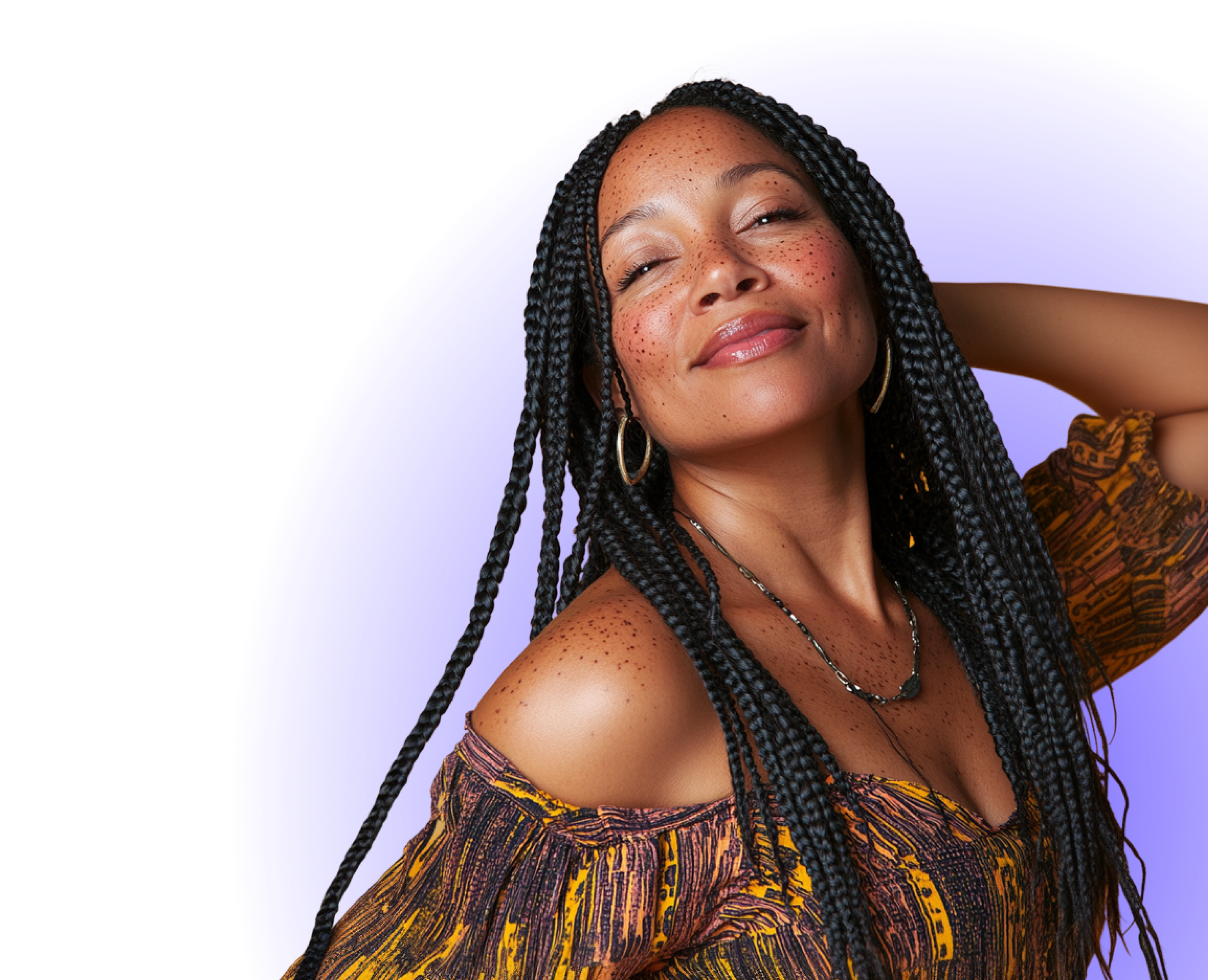 Smiling person with braided hair and freckles, wearing hoop earrings.