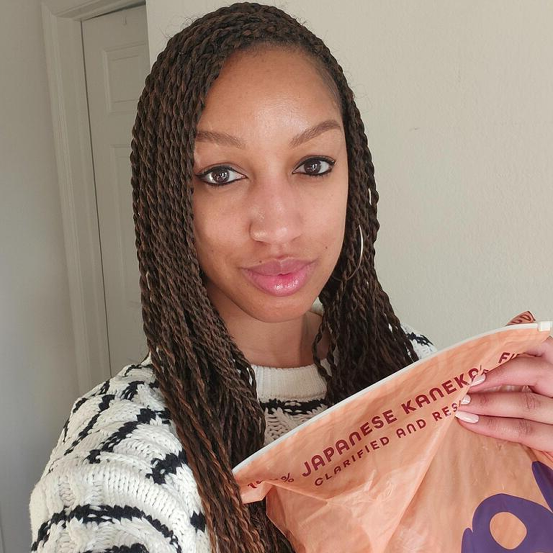 Person holding a package with text, wearing a striped sweater.