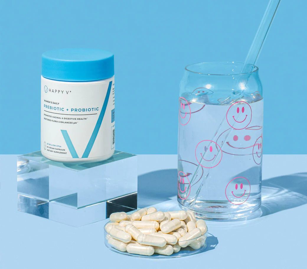 Supplement container, glass of water with smiley faces, and a dish of capsules on a blue background.