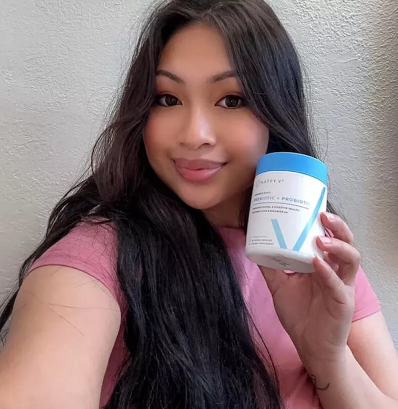 Person holding a container with blue lid, smiling at camera.