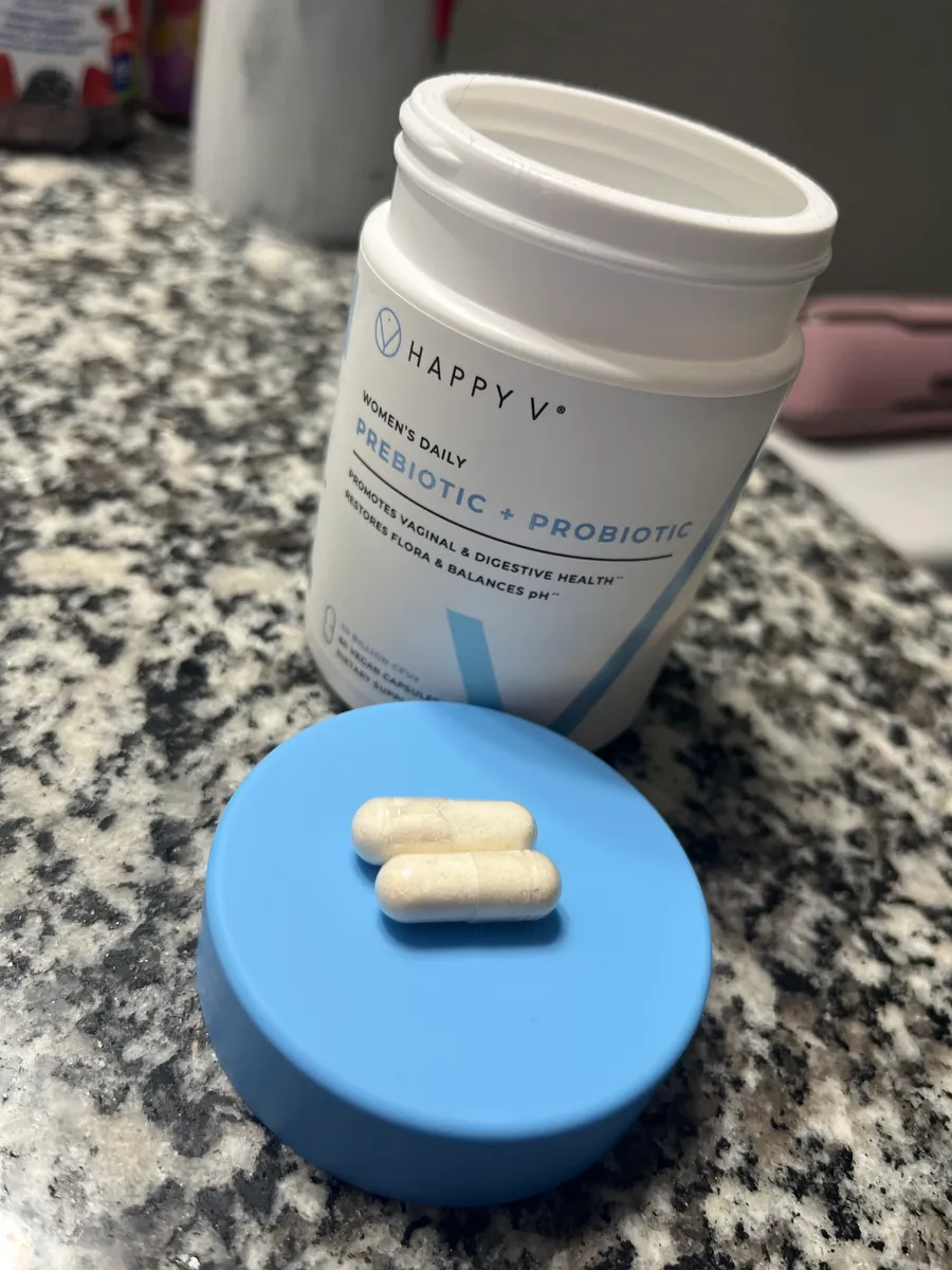 Open container of prebiotic and probiotic supplement capsules on a countertop.