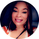 Smiling person in a car, wearing a patterned top.