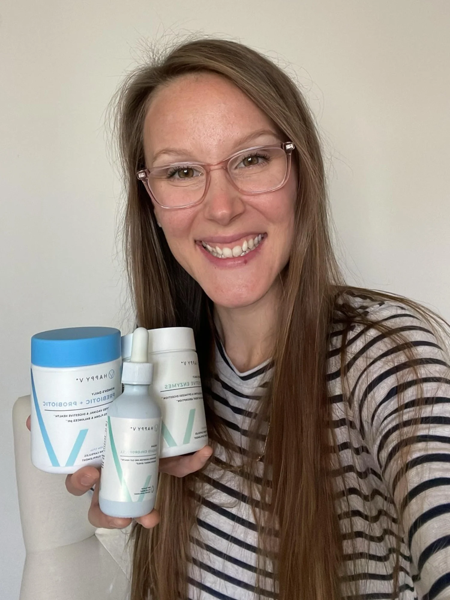 Person holding Happy V health and wellness products, smiling at the camera.
