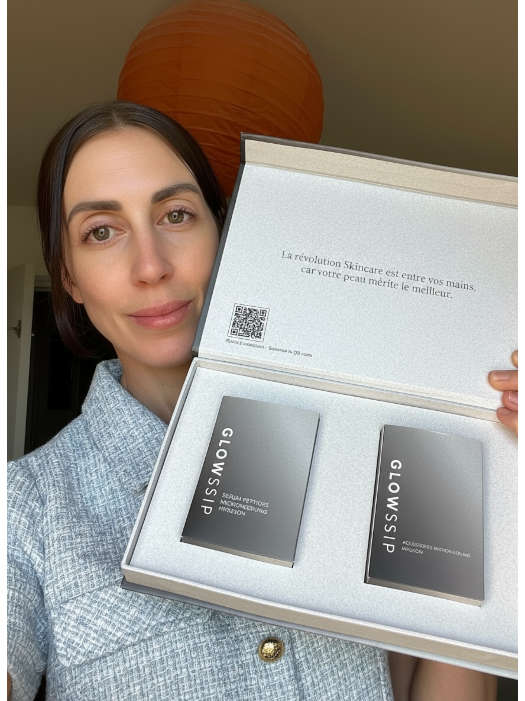 Person holding a skincare product box labeled 'GLOWSSIP' with a QR code and text in French.
