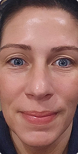 A close-up of a woman with blue eyes and dark hair looking directly at the camera with a slight smile.