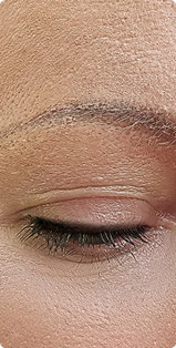 A close-up of a person's closed eye, showing the eyelid, eyelashes, and eyebrow.