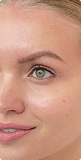 A close-up of the right side of a woman's face, focusing on her green eye and smile.
