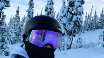 Person in ski gear with snowy trees in the background.