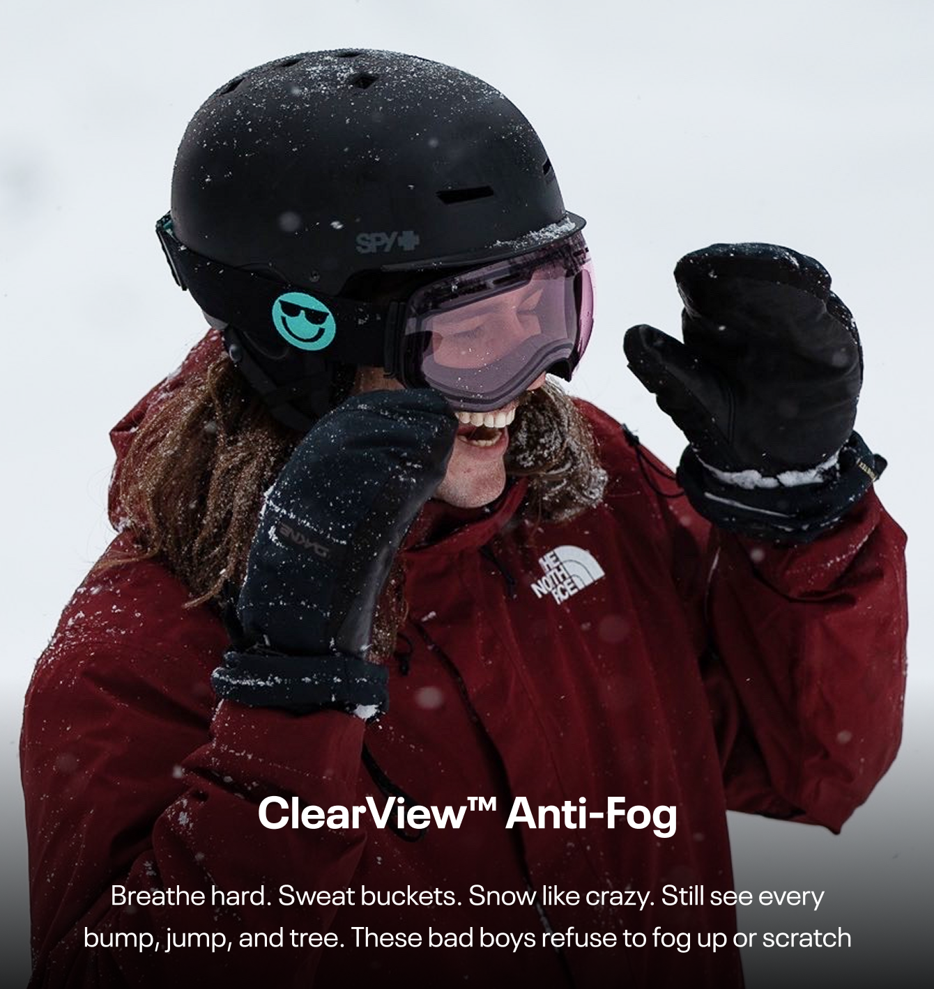 Person in red jacket and helmet, smiling in snowy conditions.