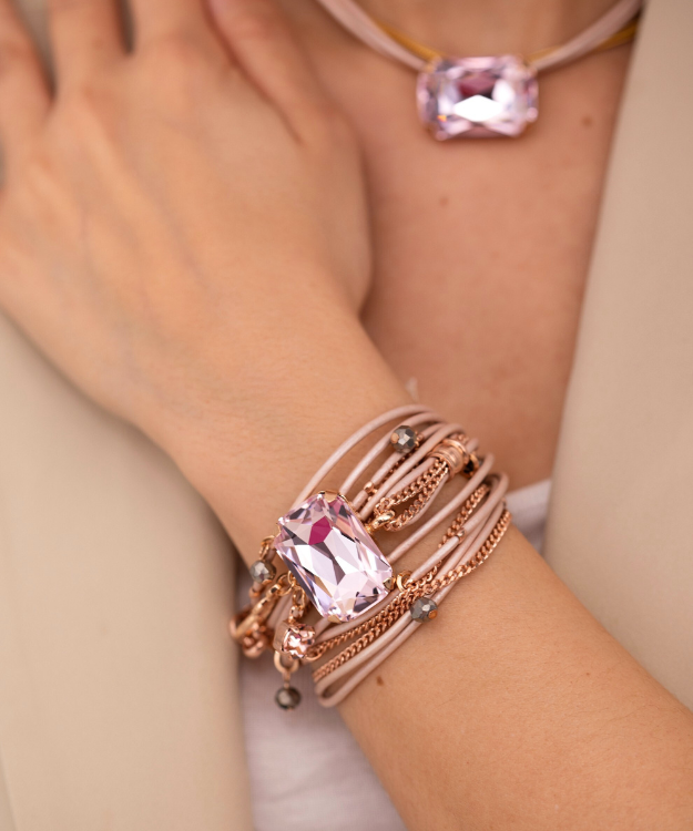 Close-up of a wrist with a pink gemstone bracelet and matching necklace.