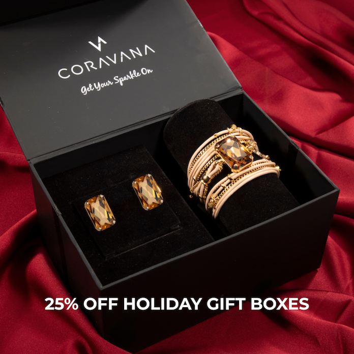 Black gift box with earrings and bracelets on red fabric background.