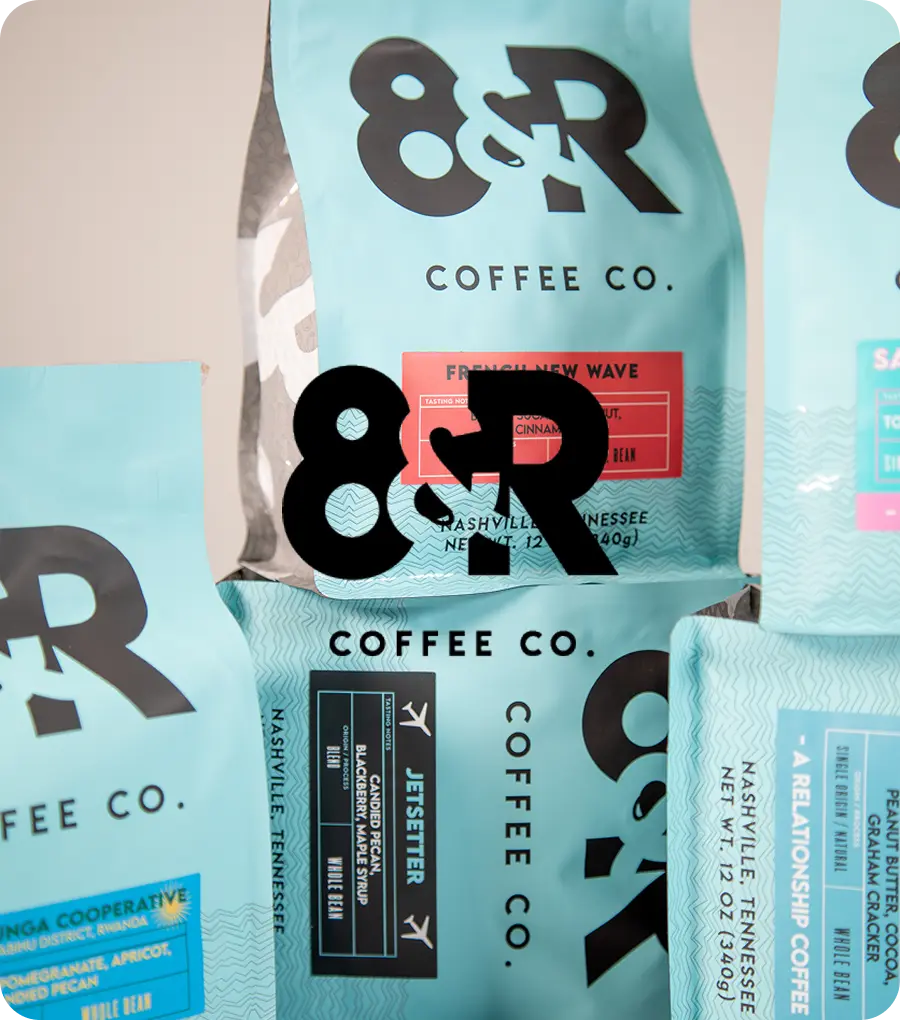 Various coffee bags from 8th & Roast with the 8th & Roast logo overlayed.