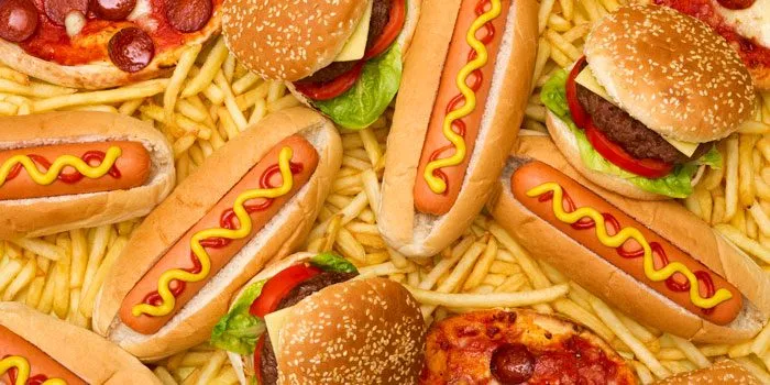 Hot dogs, burgers, and pizza on a bed of fries.