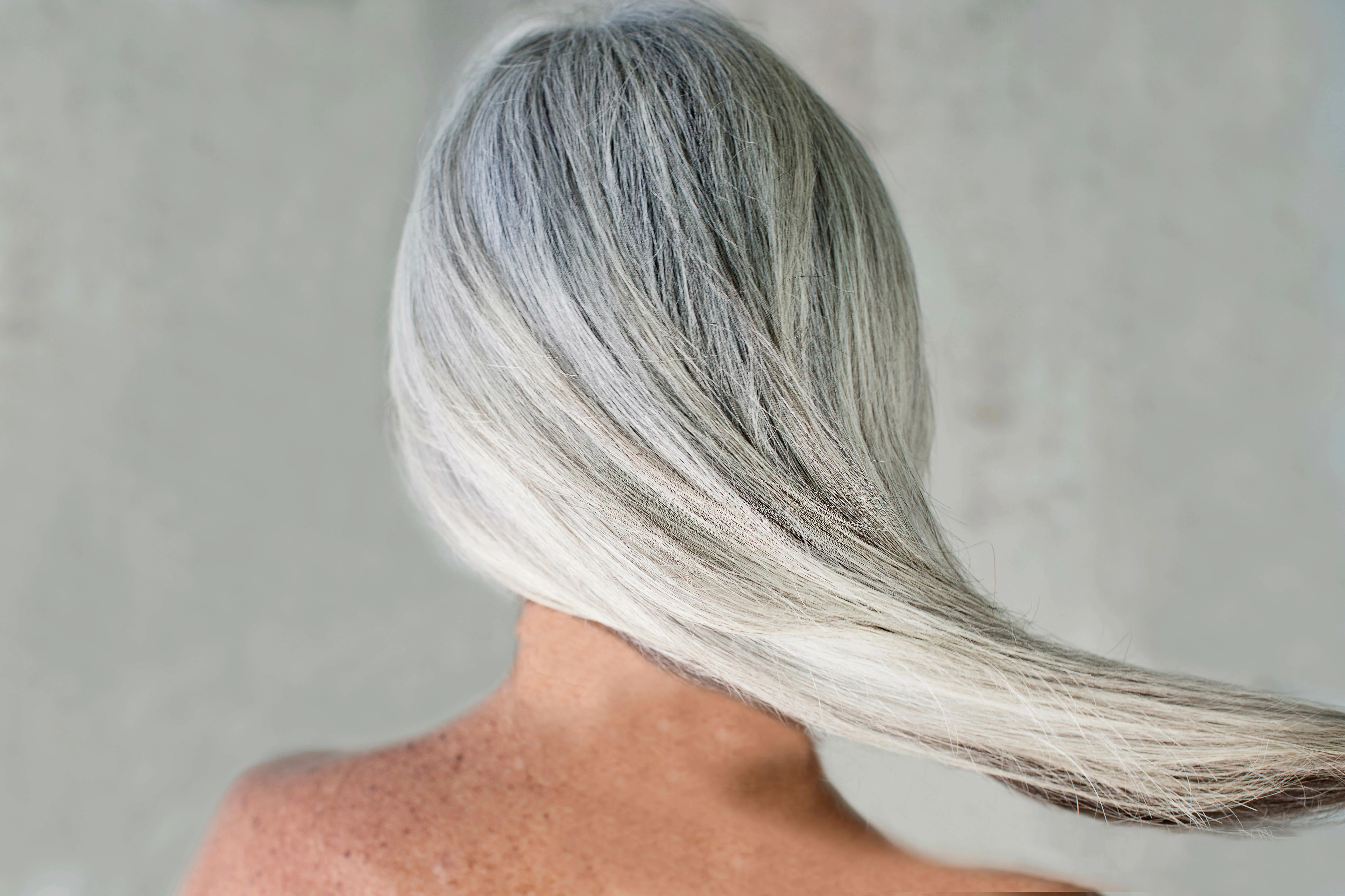 Back view of a person with long, flowing gray hair.