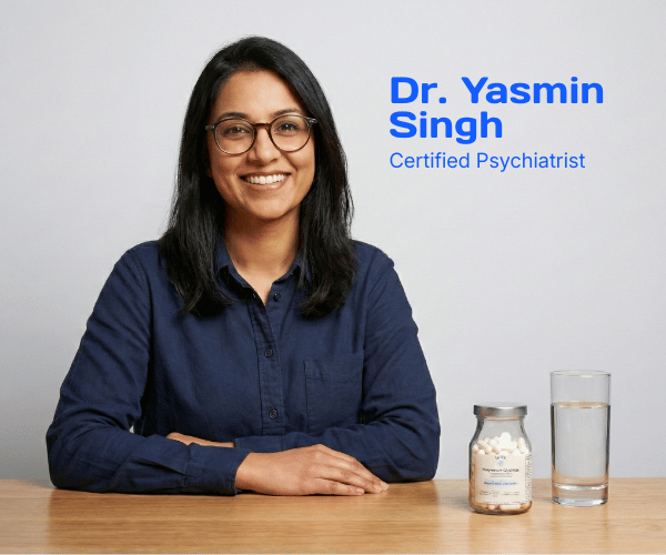 Dr. Yasmin Singh, a certified psychiatrist, sits smiling at a table with a pill bottle and glass of water.